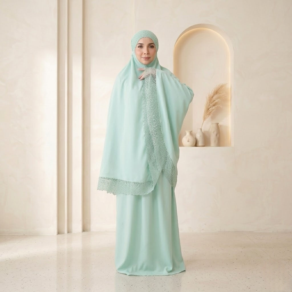 Woman wearing a light green traditional outfit with a matching headscarf in a minimalistic setting.