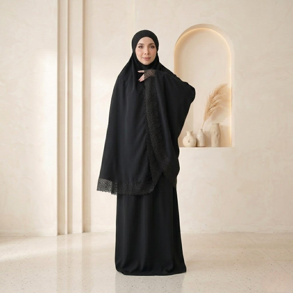 Woman wearing a black abaya with lace details in a minimalistic setting